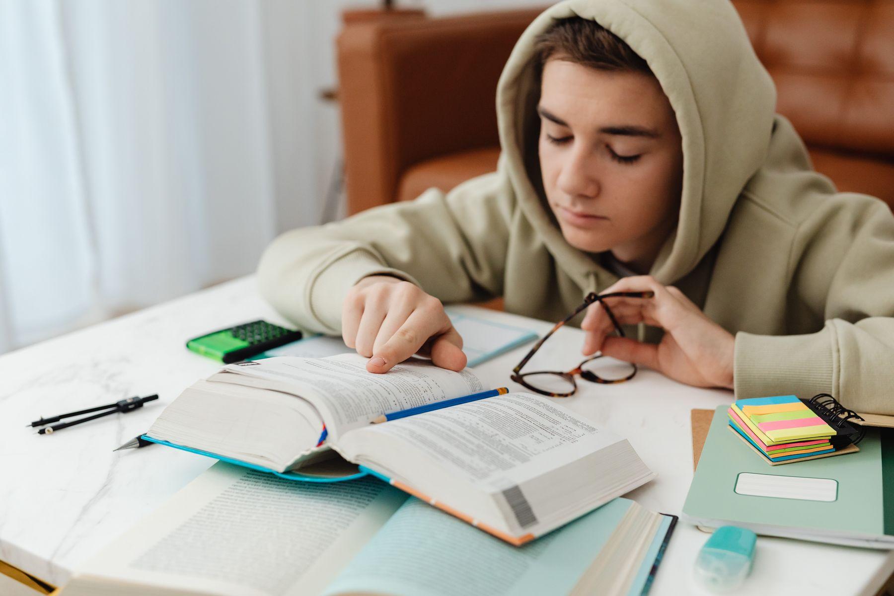Jugendlicher lernt konzentriert mit Büchern